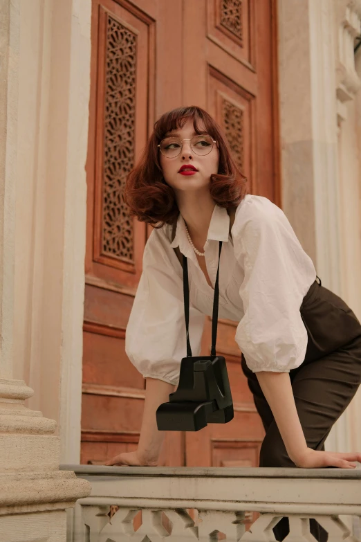 a young woman poses for the camera wearing a white blouse and black pants