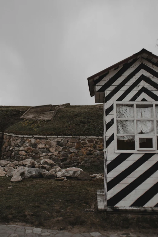 a small building has a grass area on the right and a wooden structure on the left