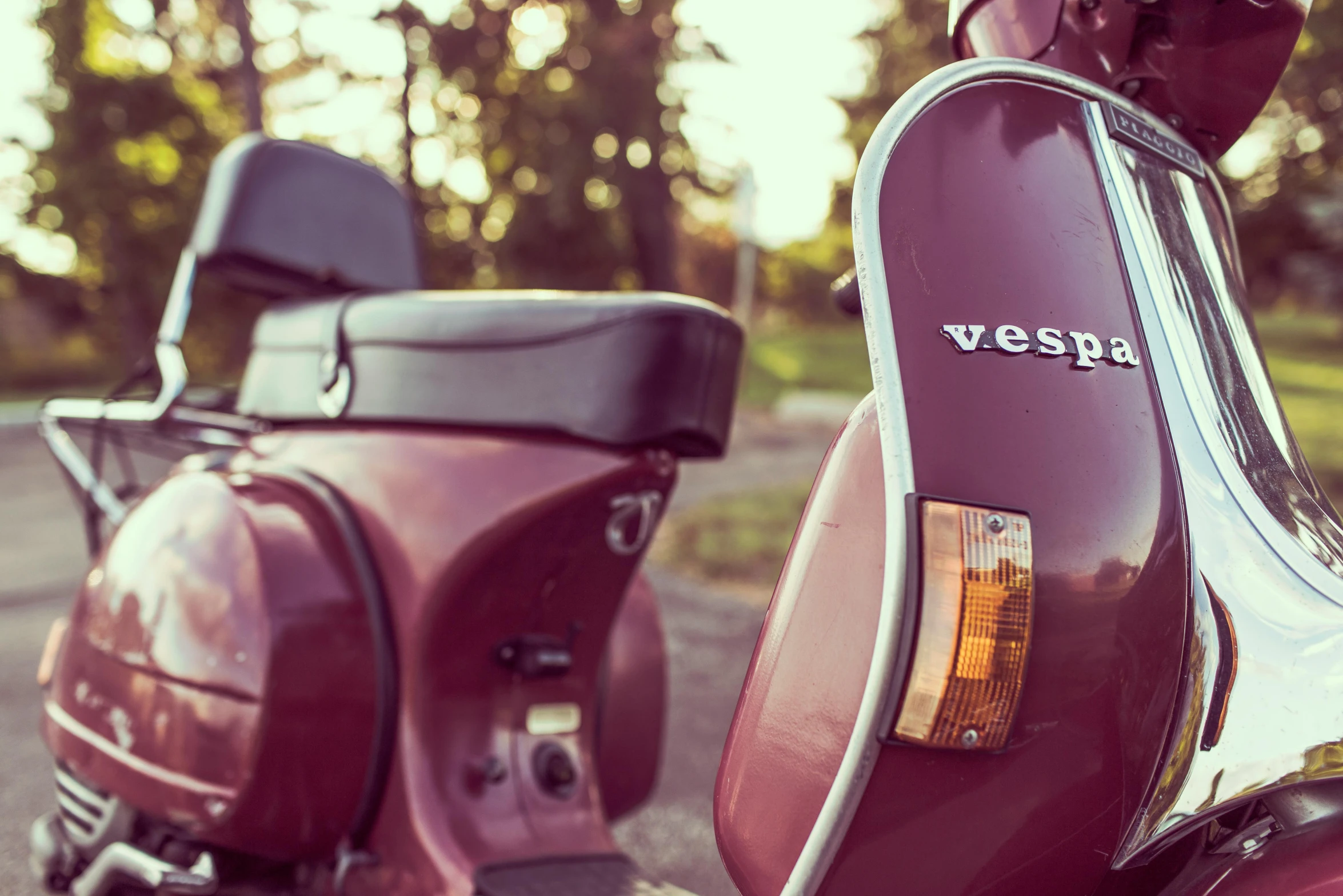 an old vintage red vespa scooter parked on the side of a road