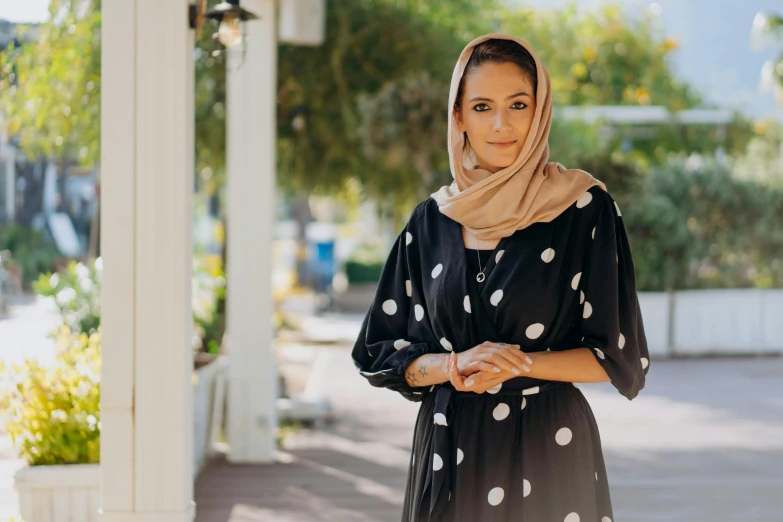 a woman standing on the porch wearing a black and white dress