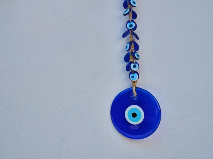 a blue evil eye hanging from a metal chain