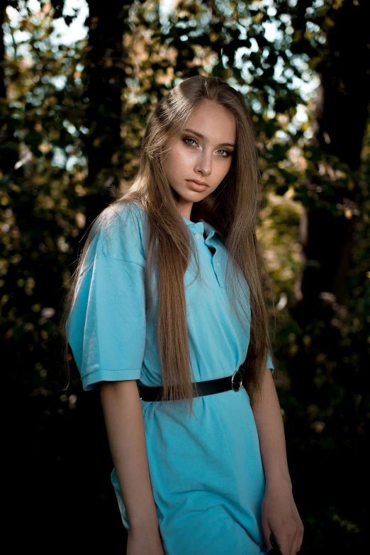 a woman with long hair standing in front of trees