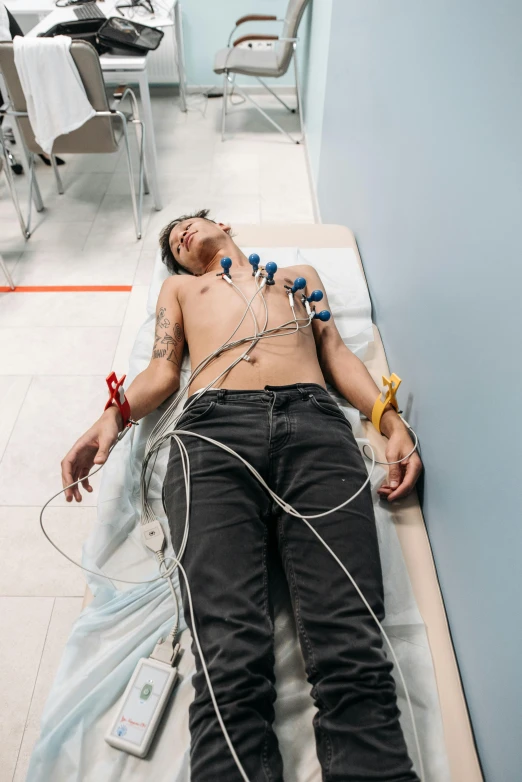 a man lying on top of a hospital bed with an electrical device attached to the stomach