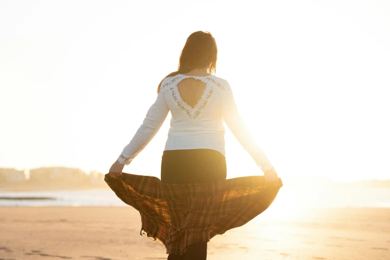 woman wearing black pants and a white top, with sun glaring over her