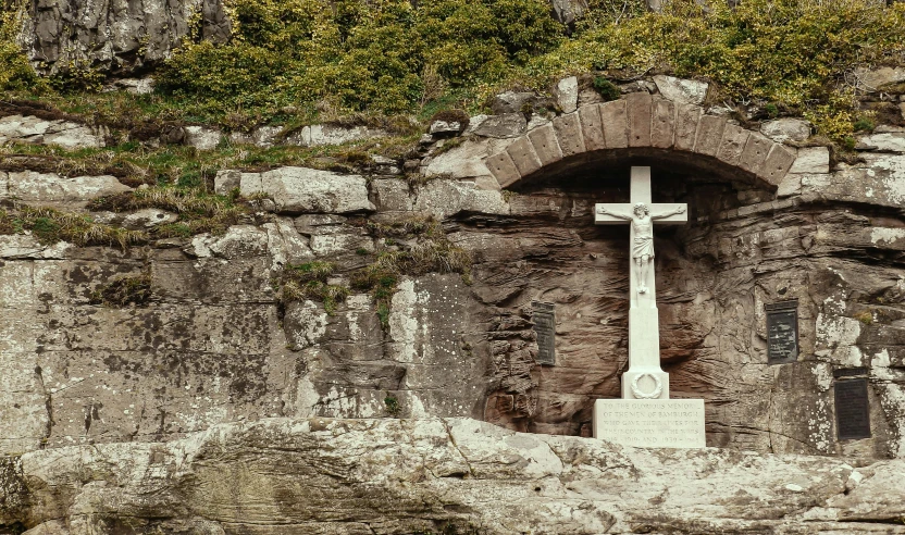 a stone wall has an ancient white cross at the top