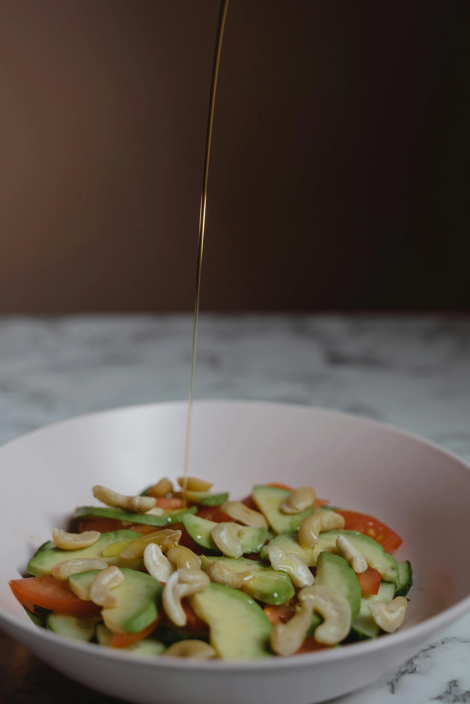 the person is sprinkling dressing on the bowl of noodles