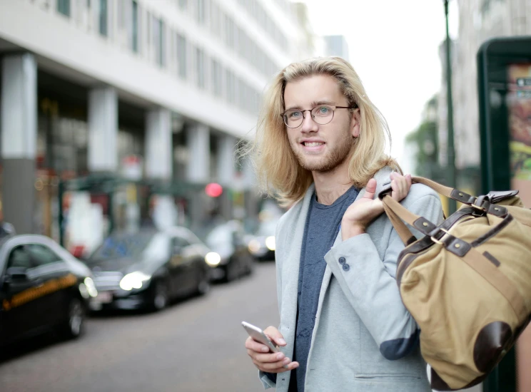 a man wearing glasses holding a bag with his luggage