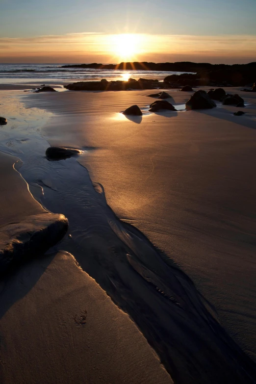 sunset reflecting off the sand as the tide begins