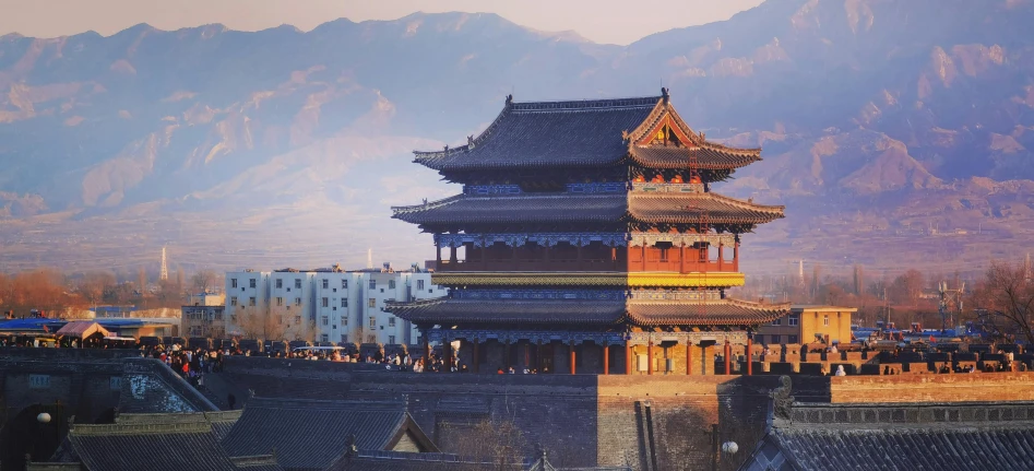 an ornate building with mountains behind it