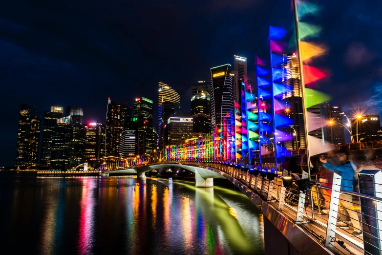 a rainbow lit bridge with city lights reflecting off the water