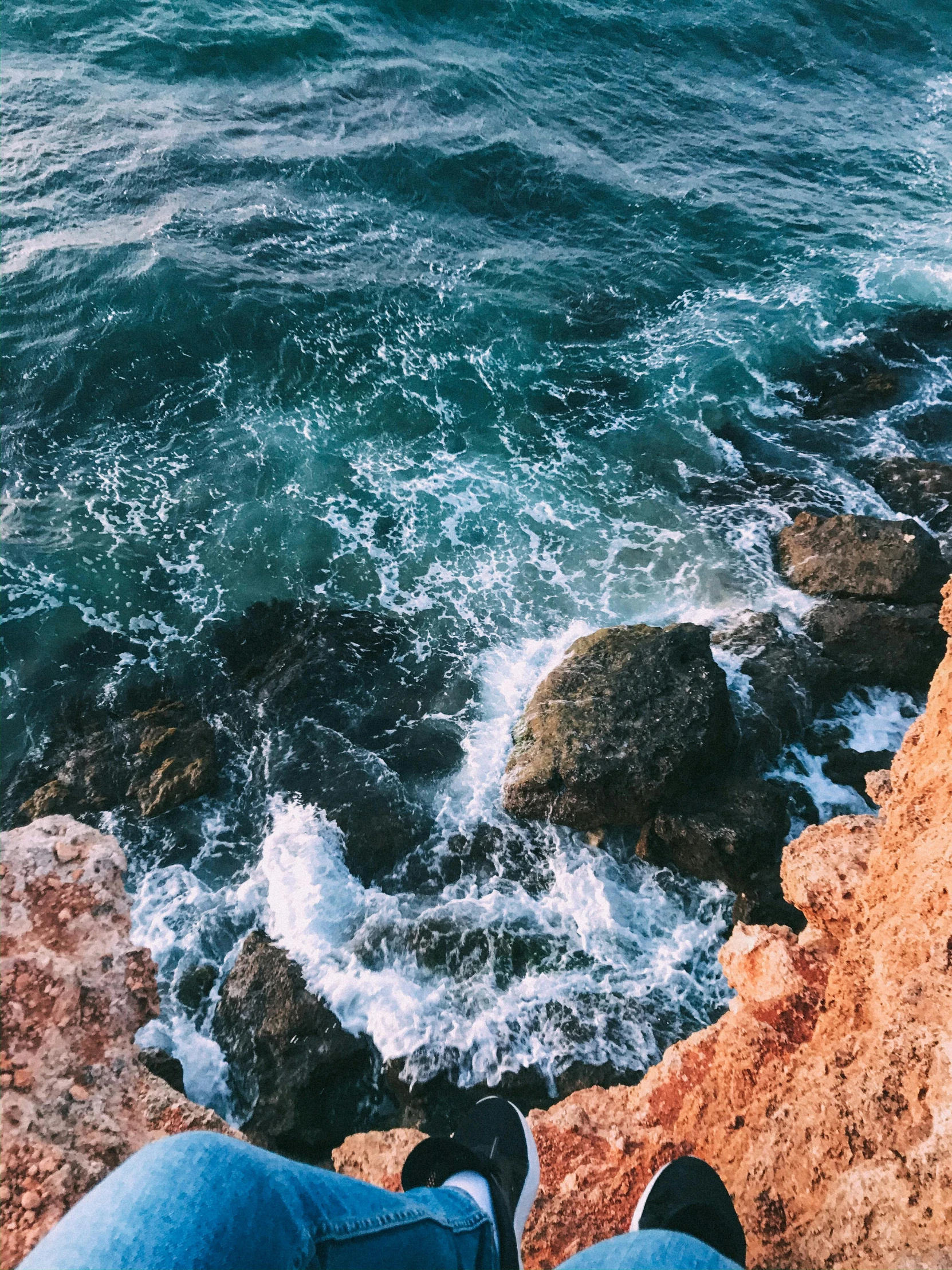 person's feet out on the rocks near water