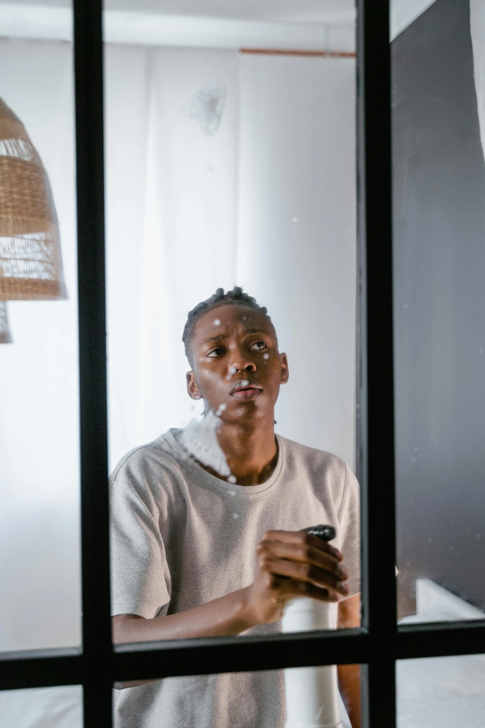 a black man looking in a mirror holding a cell phone