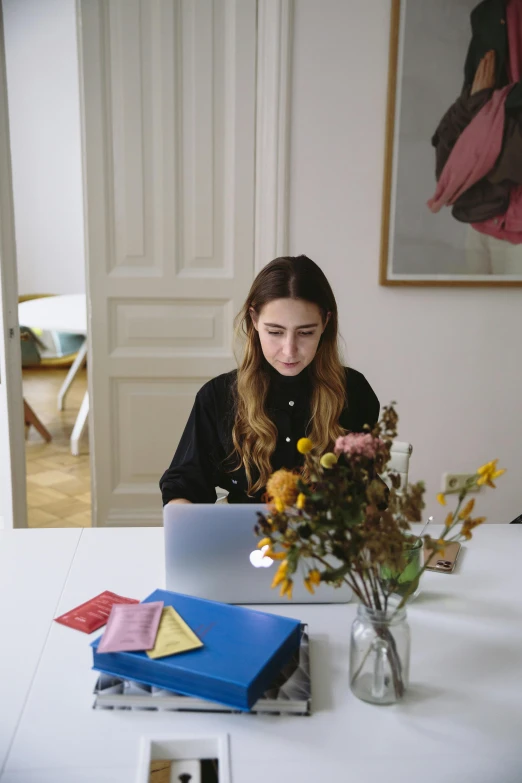 a girl sitting at a table working on a laptop