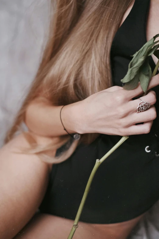 someone holding a flower and ring on their wrist