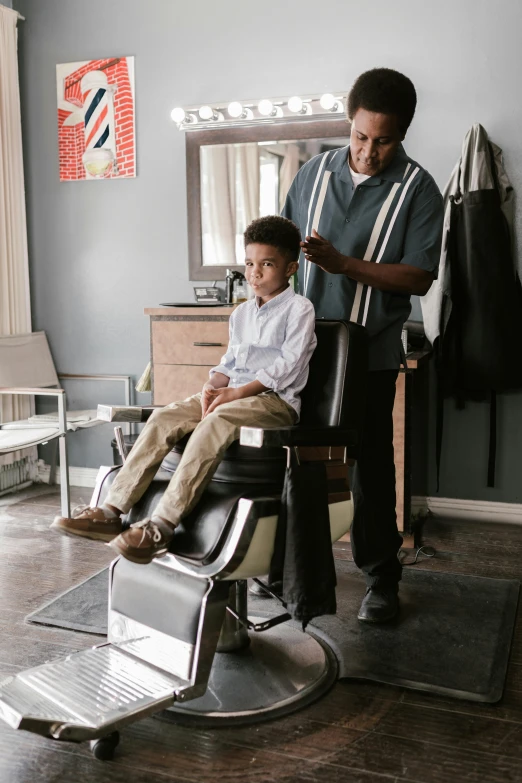 a  is having his hair cut by an older man