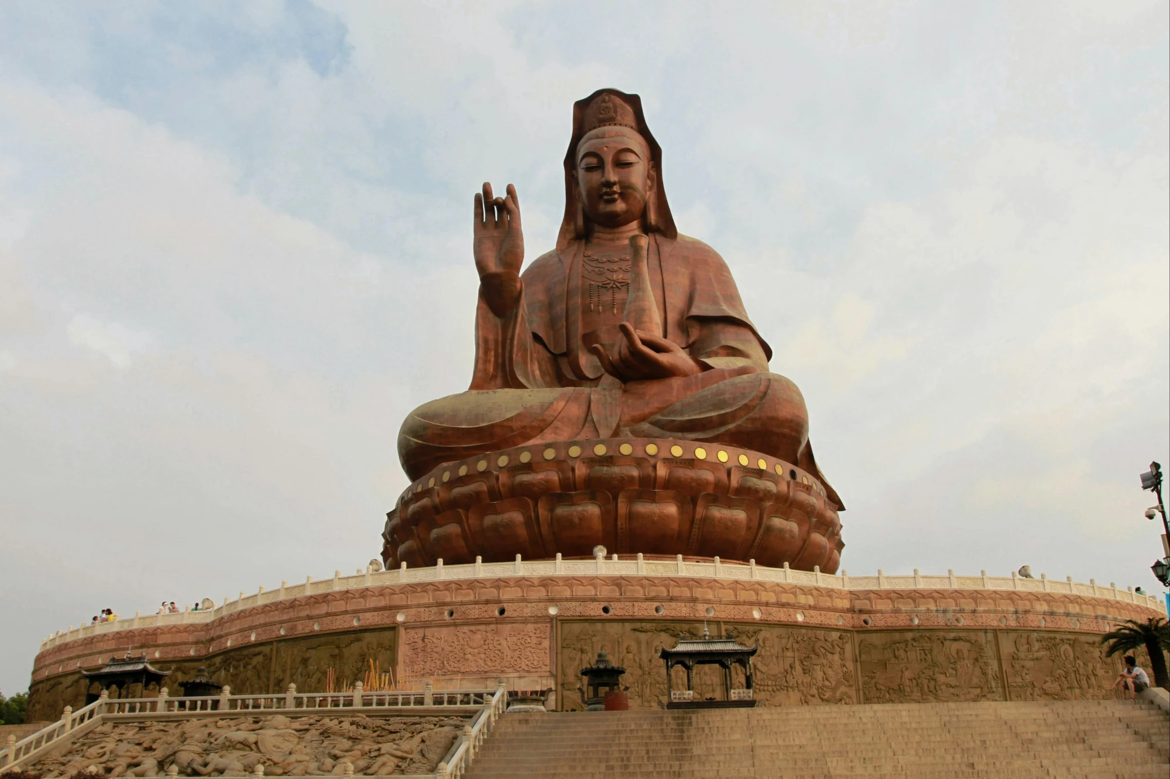 large statue of buddha standing outside near steps