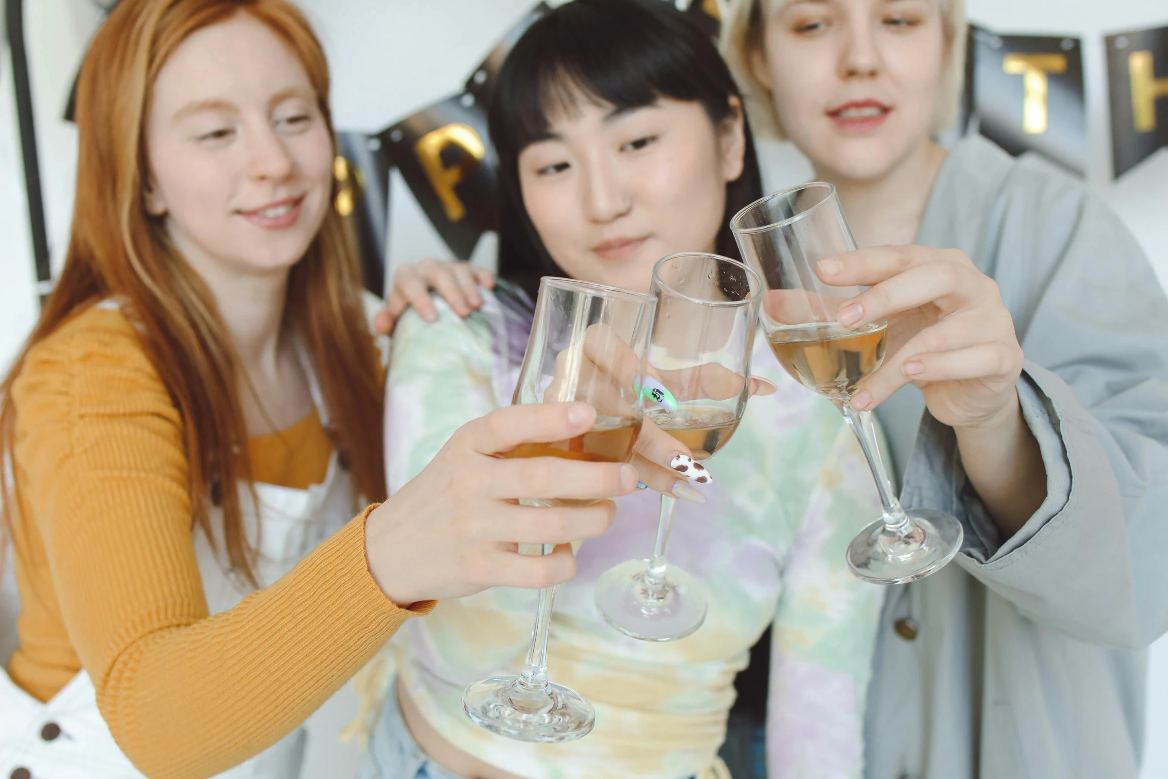 women holding wine glasses at party on sofa