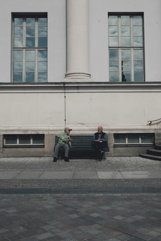 two people sitting on the edge of a sidewalk