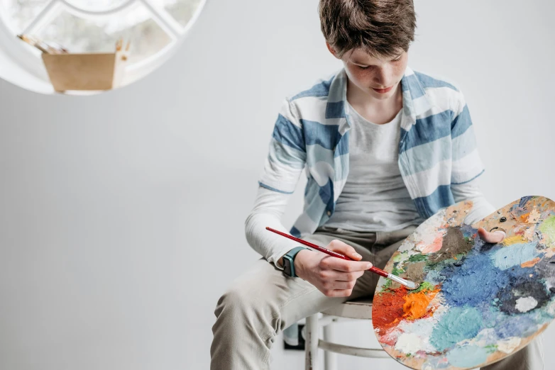 a man sitting on a stool painting with his hands