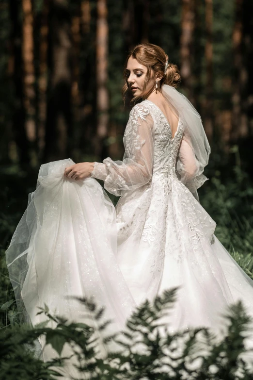 the woman in a white wedding gown is walking through the woods