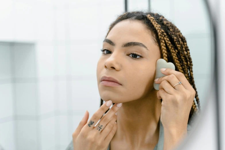 a young woman is brushing her hair and looking in the mirror