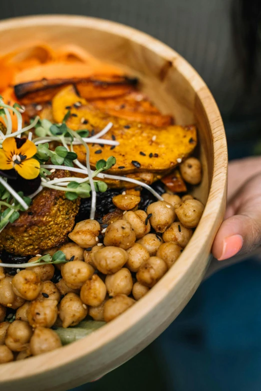 a bowl filled with vegetables and meat in a person's hands