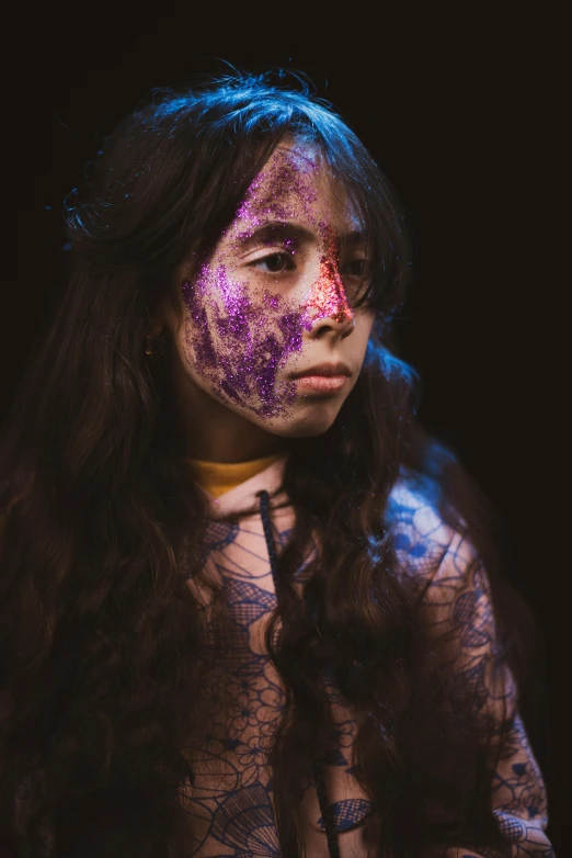 a young woman with makeup painted pink, blue and purple