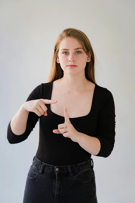 young woman in black shirt pointing at camera