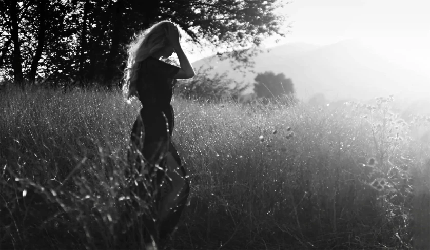 a woman standing in the grass with her hands on her face