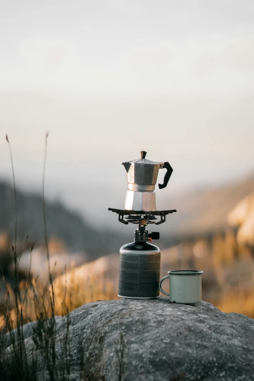 a pot with two small kettles on it on a rock