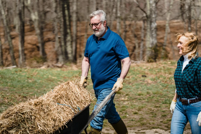 an older man and woman are pulling a bale of hay