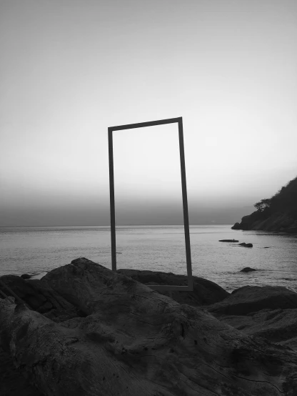 an empty wooden frame in the sand by the ocean