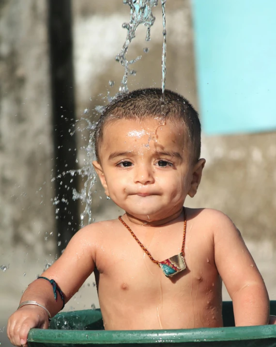 a little boy standing under a sprinkle from a sprinkle