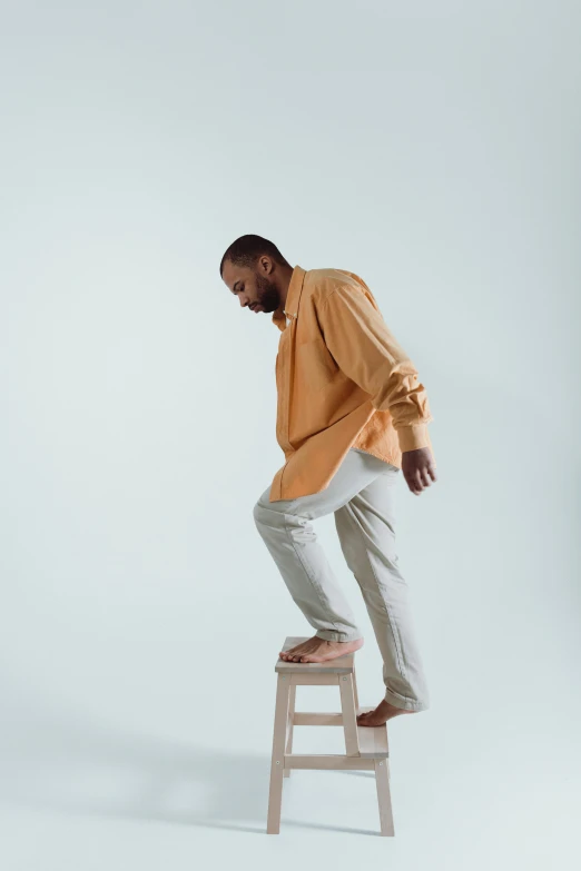 a man in a yellow shirt and white pants riding on a stool