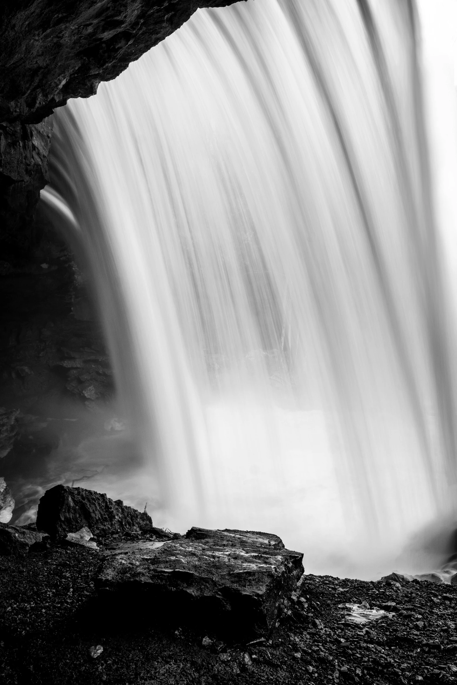 large waterfall surrounded by rocks and water