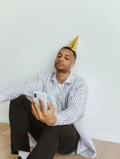 a man wearing a party hat sitting on the floor