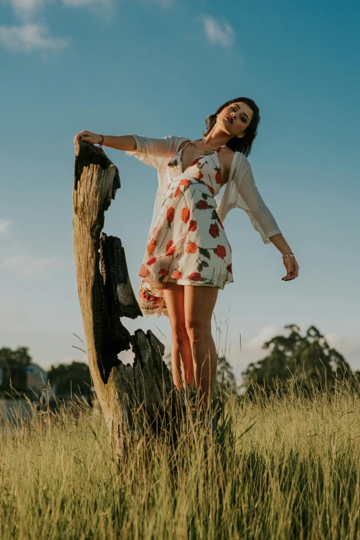 a woman leaning up against a log in a field