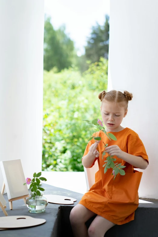 a little girl holding some flowers on her hand