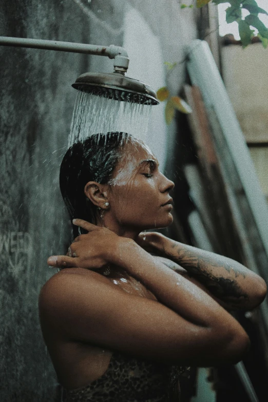 a woman holding her head in a shower, she's covered in skin