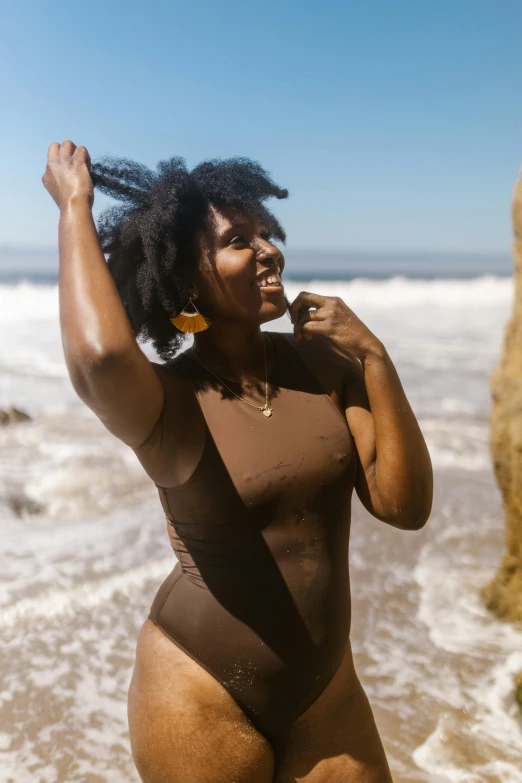 a fat black woman wearing a brown bodysuit walks along the beach