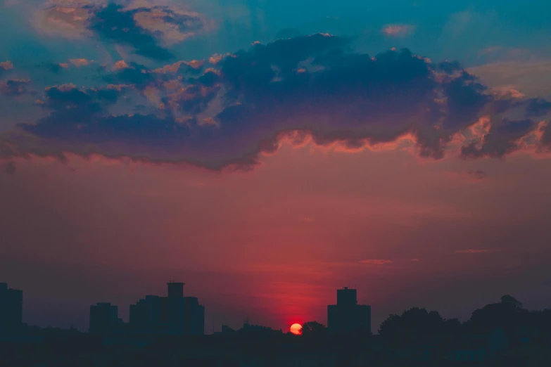 the sun is setting behind clouds that are dark and pink