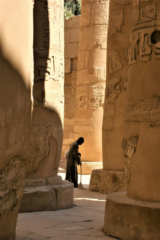 a man walking through a lot of tall stone structures