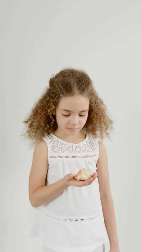 a small girl is eating an apple in front of white wall