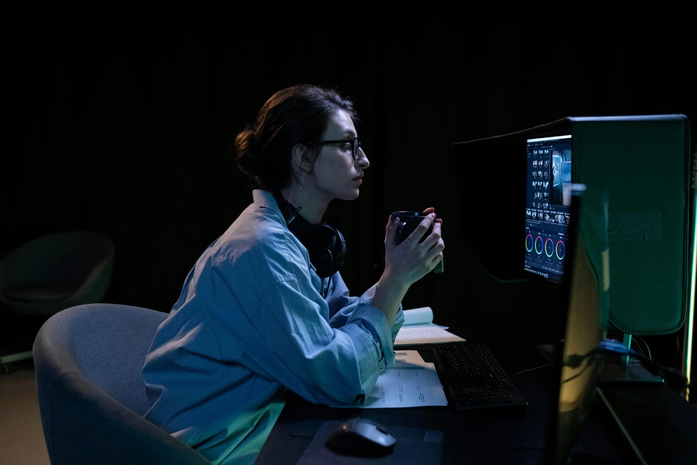 woman sitting at a table using her computer screen at night