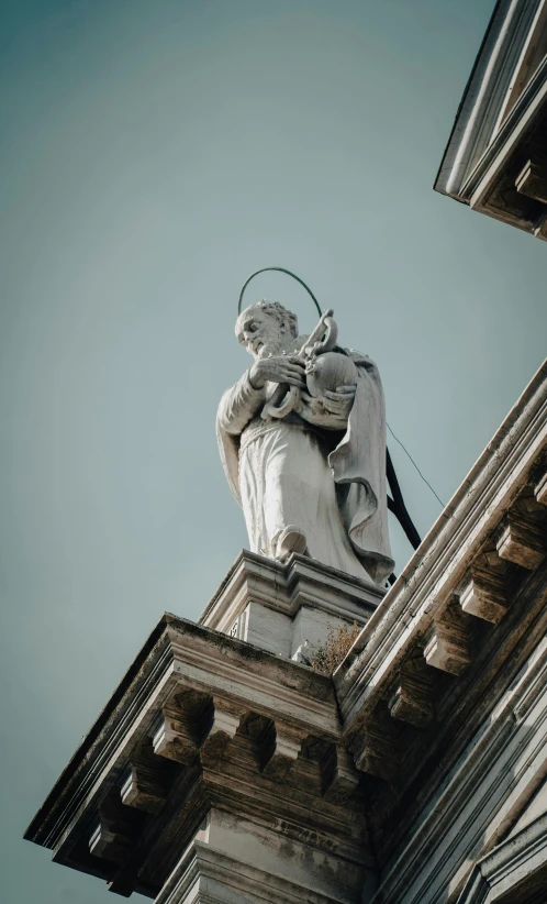 statue on top of building overlooking buildings and blue sky