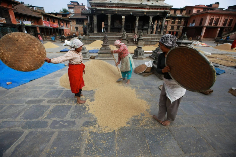 men working in the courtyard with a variety of grain