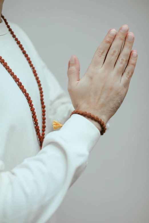 the woman in white shirt is praying and wearing a rosary