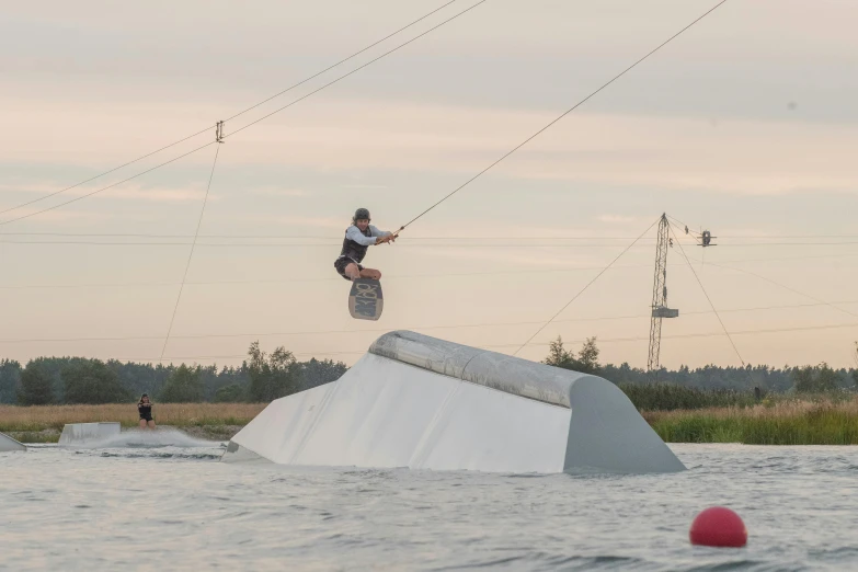 the man is holding on to his skateboard as he flies over the water