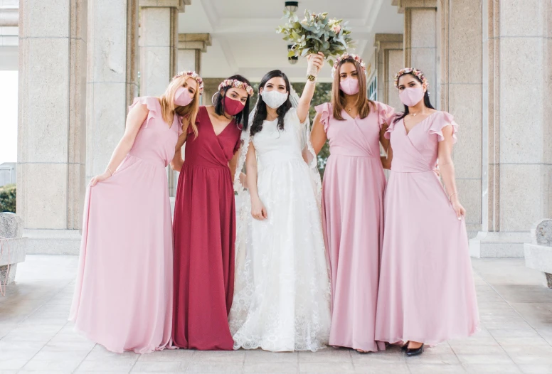 four women with long pink dresses posing for a picture