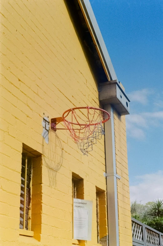 a basketball hoop mounted to the side of a yellow building